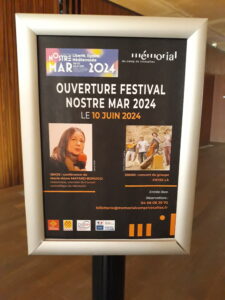 panneau représentant la conférencière et le groupe et annonçant le festival